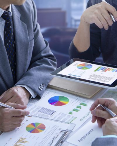 Businessmen are deeply reviewing financial reports for a return on investment or investment risk analysis and business performance.